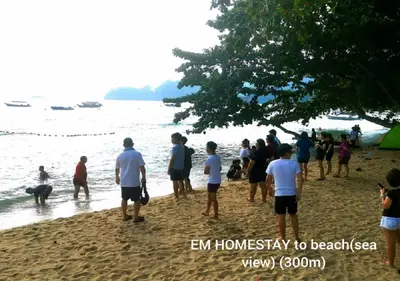 a group of people standing on a beach at EM HOMESTAY(Coral Bay 3Room Apartment) in Pangkor