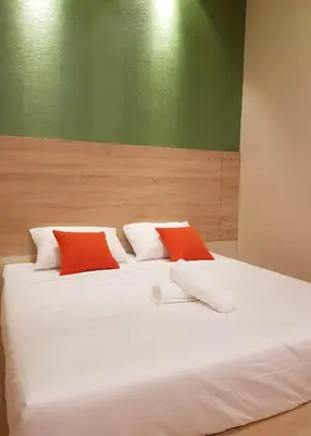 a white bed with two red pillows on it at DURIAN HILL VILLA in Gua Musang