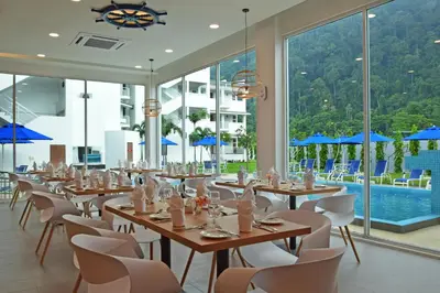 a dining room with tables and chairs and a pool at AVI Pangkor Beach Resort in Pangkor