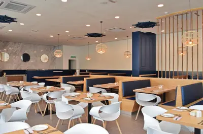 a restaurant with wooden tables and white chairs at AVI Pangkor Beach Resort in Pangkor