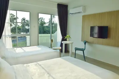 a hotel room with two beds and a window at AVI Pangkor Beach Resort in Pangkor