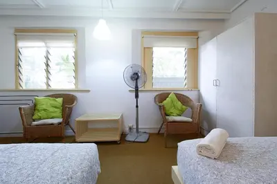 a bedroom with two beds and two chairs and a fan at Bellevue The Penang Hill Hotel, Bukit Bendera in Ayer Itam