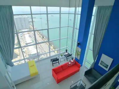 a room with a red couch in front of a large window at Maritime Suites by Comfy in George Town