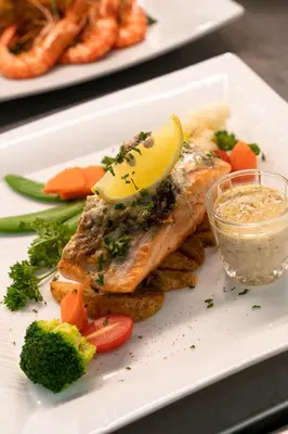 a white plate with fish with a lemon on top at Travelodge Ipoh in Ipoh
