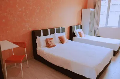 a bedroom with two beds and a table and a chair at OK FAMILY VILLA in Ipoh