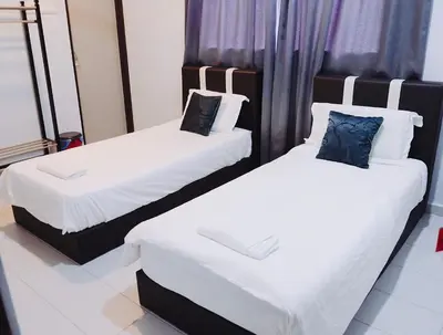 two beds in a room with white sheets and blue pillows at OK FAMILY VILLA in Ipoh