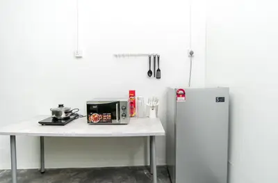 a table with a microwave and a refrigerator in a kitchen at Abu Siti George Town in George Town