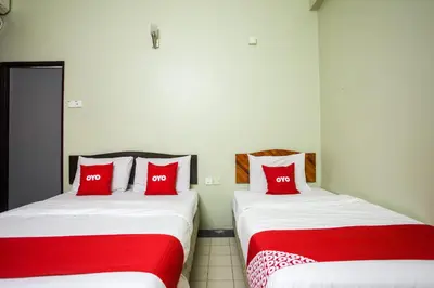 two beds with red pillows in a room at OYO 89549 Casavilla Hotel (city Centre) Taiping in Taiping