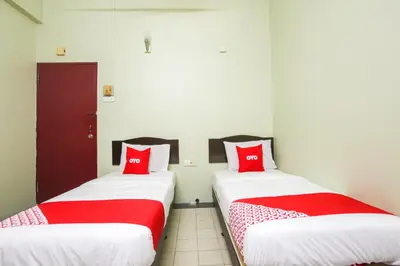 two beds in a room with red pillows at OYO 89549 Casavilla Hotel (city Centre) Taiping in Taiping