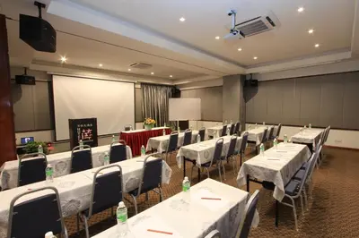 a conference room with white tables and chairs and a screen at Ipoh Downtown Hotel in Ipoh