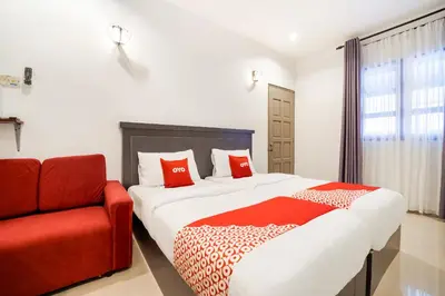 a bedroom with a large bed and a red chair at Hotel O Kulim Inn in Kulim