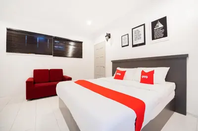 a bedroom with a bed and a red chair at Hotel O Kulim Inn in Kulim