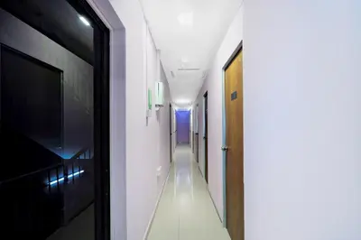 a hallway with white walls and a door and a hallway with white floors at Hotel O City Hostel Ipoh in Ipoh