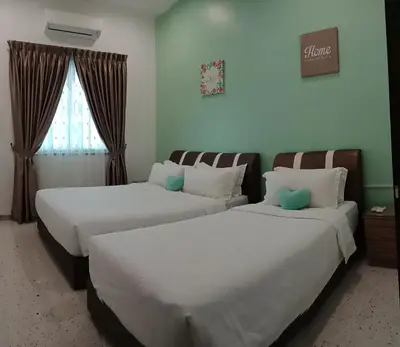 two beds in a hotel room with a window at Austin Homestay in Ipoh