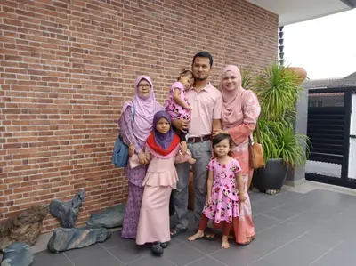 a family poses for a picture in front of a brick wall at Austin Homestay in Ipoh