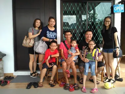 a family posing for a picture in front of a house at Austin Homestay in Ipoh