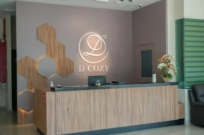 a reception desk in a lobby with a logo on the wall at DCozy Hotel in Perai
