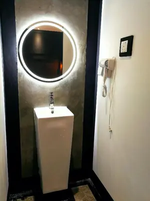 a bathroom with a urinal and a round mirror at CJ HOUSE station 18 Ipoh in Ipoh
