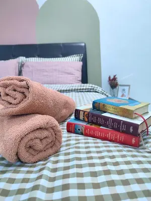 a pile of books and towels on a bed at Rara Homestay Kuala Kangsar in Kuala Kangsar