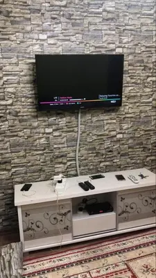 a tv on a stone wall with a table with a television on it at Muslim Apartment Homestay in Tanah Rata