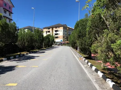 an empty street with trees and buildings in the distance at Muslim Apartment Homestay in Tanah Rata