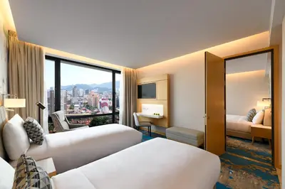 a hotel room with two beds and a large window at OZO George Town Penang in George Town