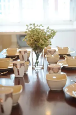 a table with plates and a vase of flowers on it at By the sea Duplex penthouse baby in Batu Ferringhi