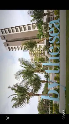 a tall building with palm trees in front of it at By the sea Duplex penthouse baby in Batu Ferringhi