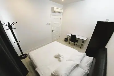 a bedroom with a bed with white sheets and a desk at Island Hostel Bayan Lepas Airport in Bayan Lepas