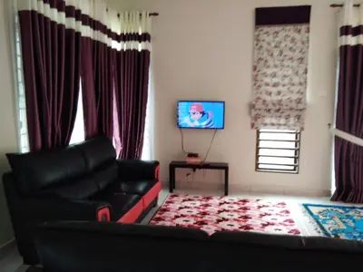 a living room with a couch and a television at Cozy Corner Homestay in Kepala Batas