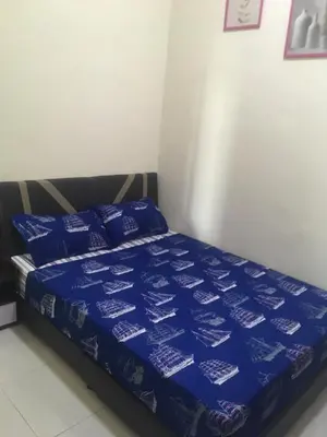 a bed with a blue comforter and pillows on it at Cozy Corner Homestay in Kepala Batas