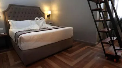 a bedroom with a bed with white sheets and a ladder at 1969 Business Suites @ Ipoh Garden in Ipoh