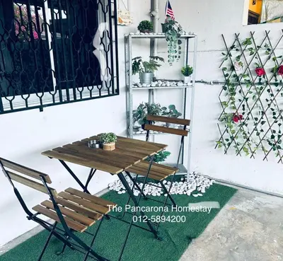 a table and a bench next to a wall with plants at The Pancarona Homestay forMuslims, Ipoh, Perak in Ipoh
