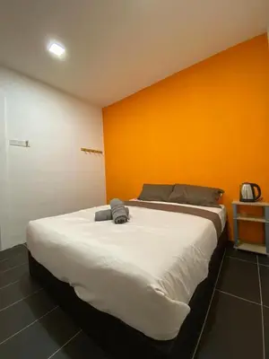 a large bed in a room with an orange wall at YipStay in Gopeng