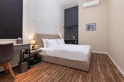 a bedroom with a white bed and a desk at Wesley Hotel in Bukit Mertajam