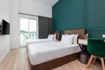 a bedroom with two beds and a desk and a green wall at Wesley Hotel in Bukit Mertajam
