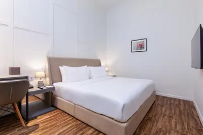 a bedroom with a large white bed and a desk at Wesley Hotel in Bukit Mertajam