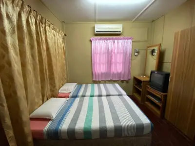 a small room with two beds and a television at PANGKOR PURNAMA CHALET in Pangkor