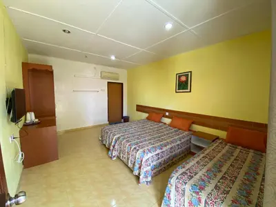 a hotel room with two beds and yellow walls at PANGKOR PURNAMA CHALET in Pangkor