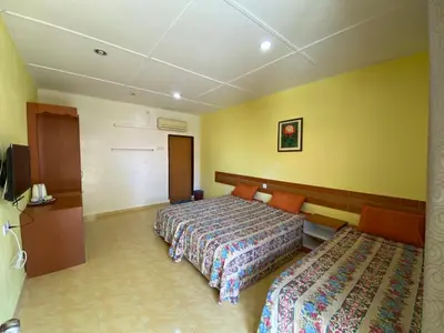 a hotel room with two beds and yellow walls at PANGKOR PURNAMA CHALET in Pangkor