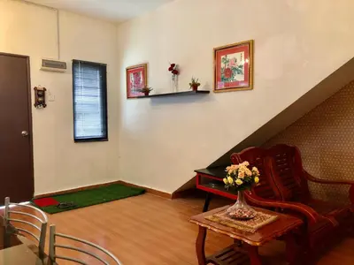 a living room with a staircase with a chair and a table at Sinar Ara homestay in Lunas