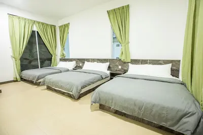 two beds in a bedroom with green curtains at Barrington Villa @ Golden Hill in Cameron Highlands