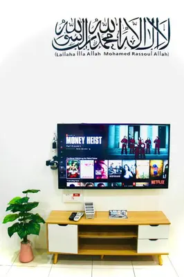 a living room with a tv on a wall at Bismillah Homestay Muslem NETFLIX UNIFI HIGH SPEED in Kamunting