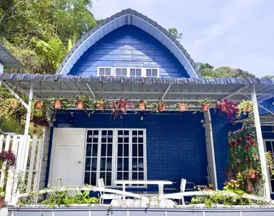 a blue house with a table and chairs in front of it at Blue Cabins By Pfordten Cottage in Cameron Highlands
