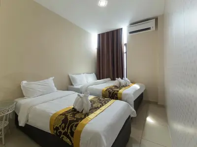 a hotel room with two beds with cats sitting on them at Top Garden Hotel in Hutan Melintang