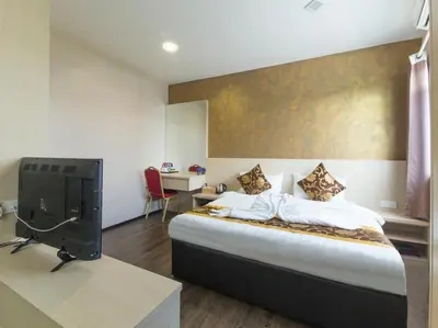 a bedroom with a bed and a desk with a tv at Top Garden Hotel in Hutan Melintang