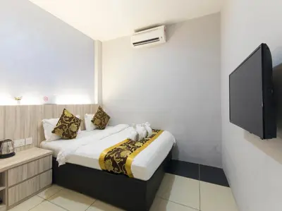 a hotel room with a bed and a flat screen tv at Top Garden Hotel in Hutan Melintang