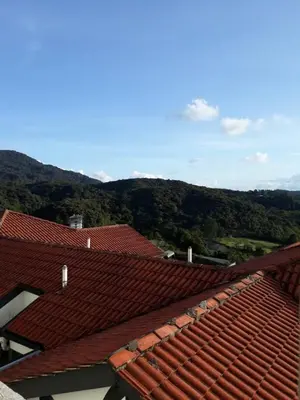a view of the roofs of two buildings with mountains in the background at Merlin Home@Crown Imperial Court in Tanah Rata