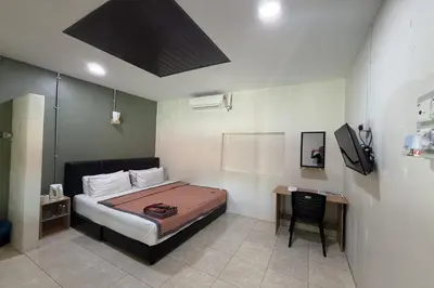 a bedroom with a bed and a desk with a television at Inapan Taman Herba in Kepala Batas