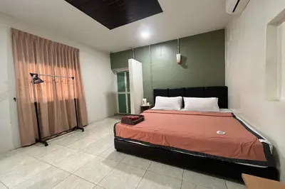 a bedroom with a bed with a red comforter at Inapan Taman Herba in Kepala Batas